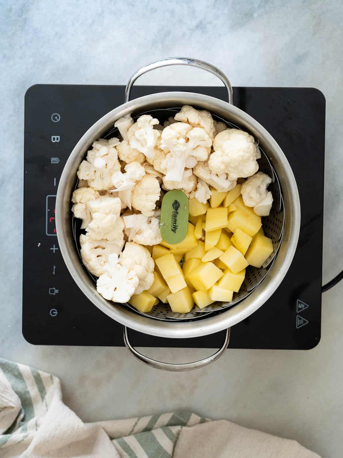 coliflor y papas al vapor en una cacerola lista para preparar ensalada.