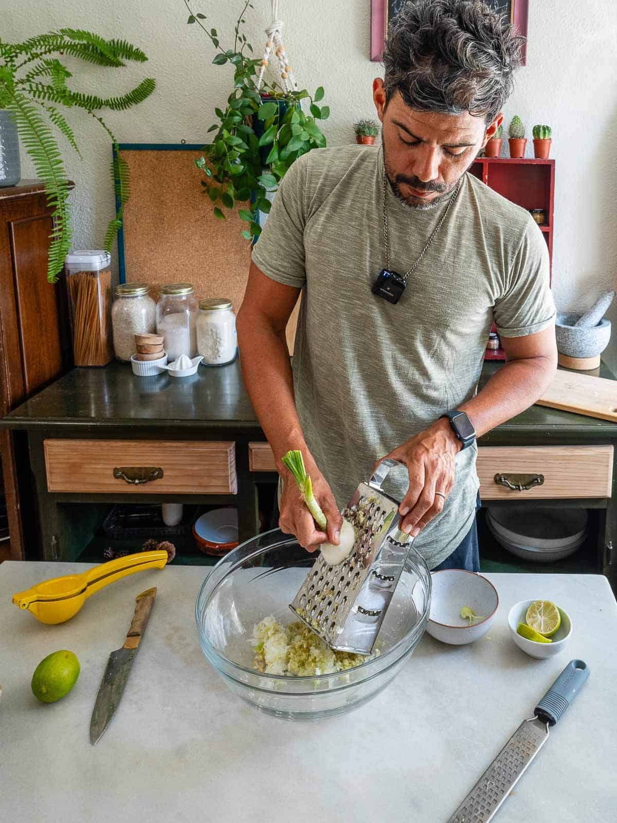 hombre rallando cebolleta fresca en un bol transparente para ensalada.