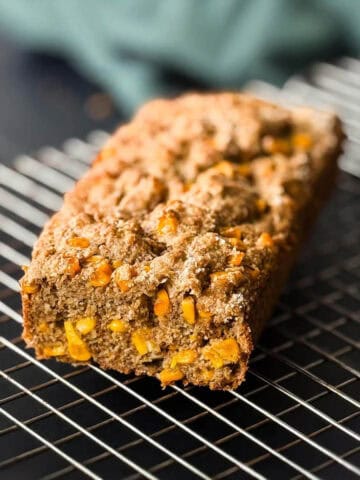 Pastel de choclo vegano enfriándose sobre una rejilla metálica, con una textura dorada y granulada en el exterior.