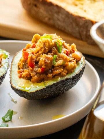 Aguacate relleno decorado con hierbas frescas y un chorrito de aceite de oliva.