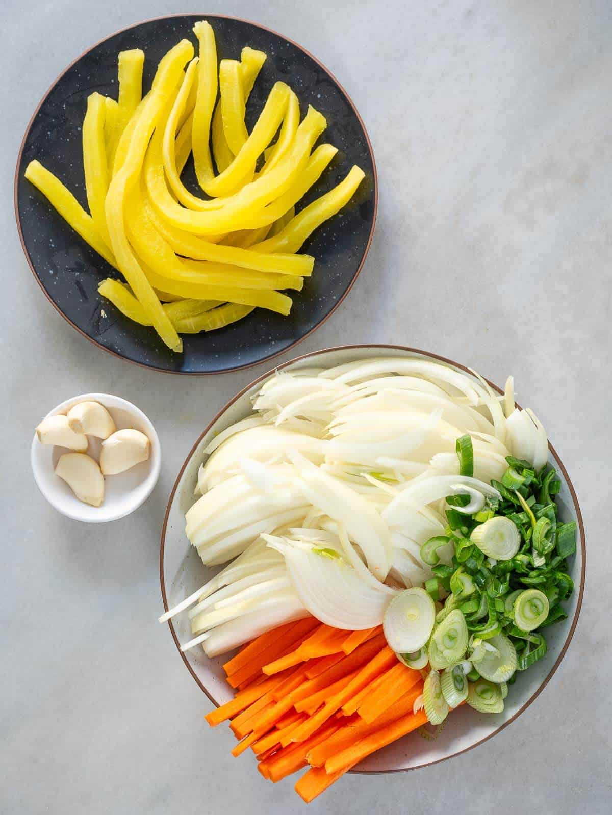 Ingredientes frescos para kimchi vegano: rábano daikon, zanahoria, cebolla, ajo y cebolleta en rodajas. Preparación de la mezcla de vegetales para una receta fermentada auténtica.