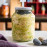 Receta de chucrut casero en un frasco con tapa especial para fermentación, ideal para obtener probióticos naturales en casa.