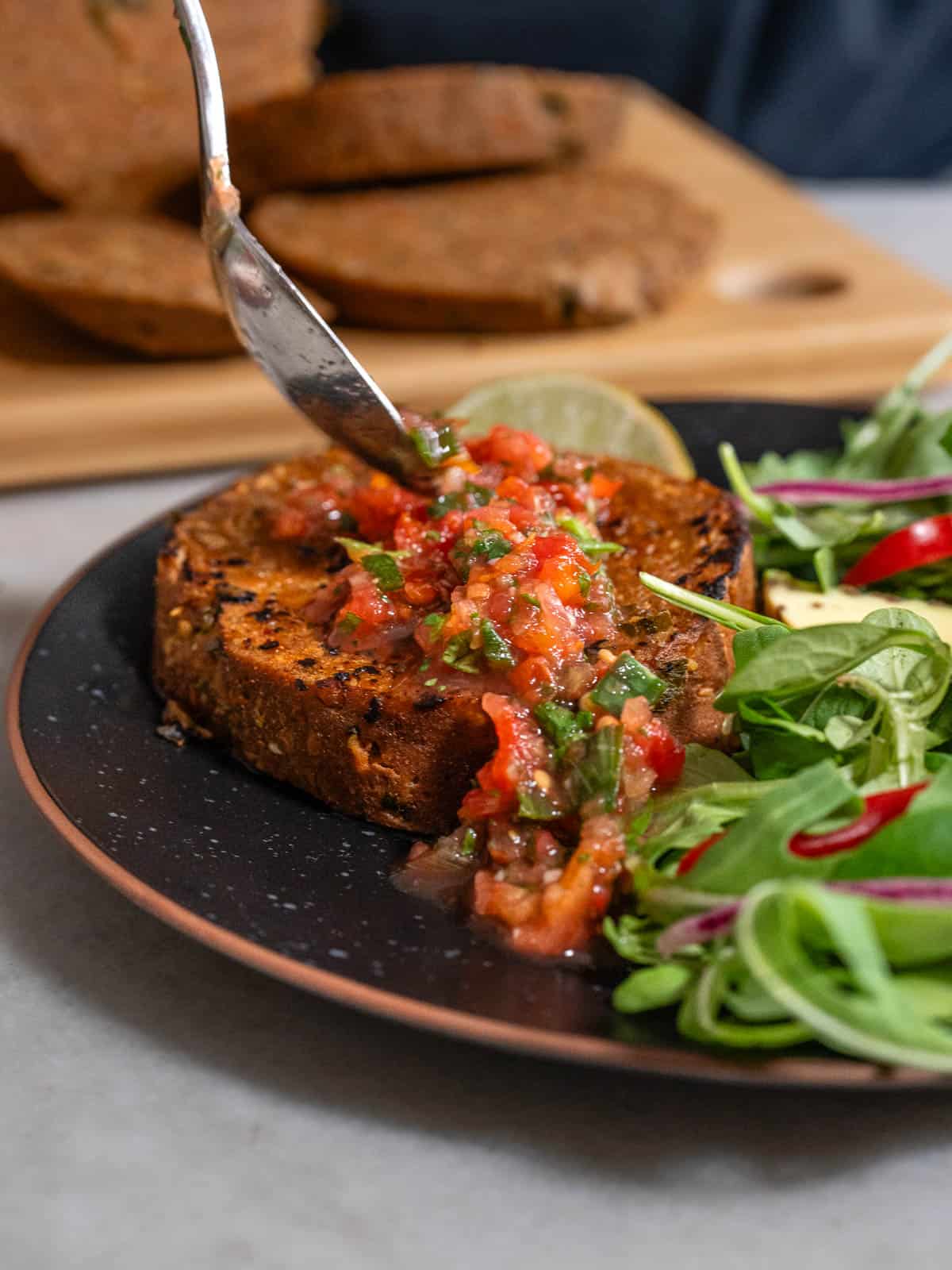 Rebanada de seitán dorado con ensalada fresca y una generosa cucharada de pico de gallo casero encima.
