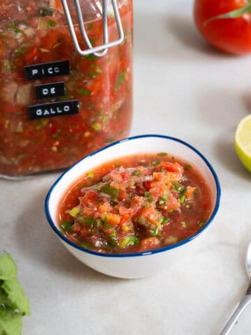 Primer plano del pico de gallo en un bol blanco, mostrando su textura fresca y colorida.
