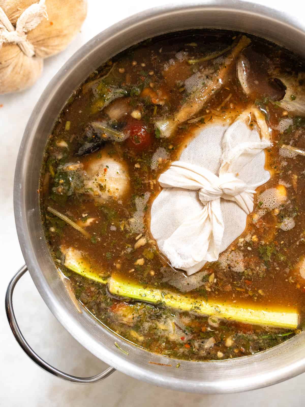 Seitán casero envuelto en tela de cocina, cocinándose en una olla con caldo vegetal casero lleno de hierbas, verduras y especias. Receta vegana rica en proteína vegetal, sin ingredientes animales.