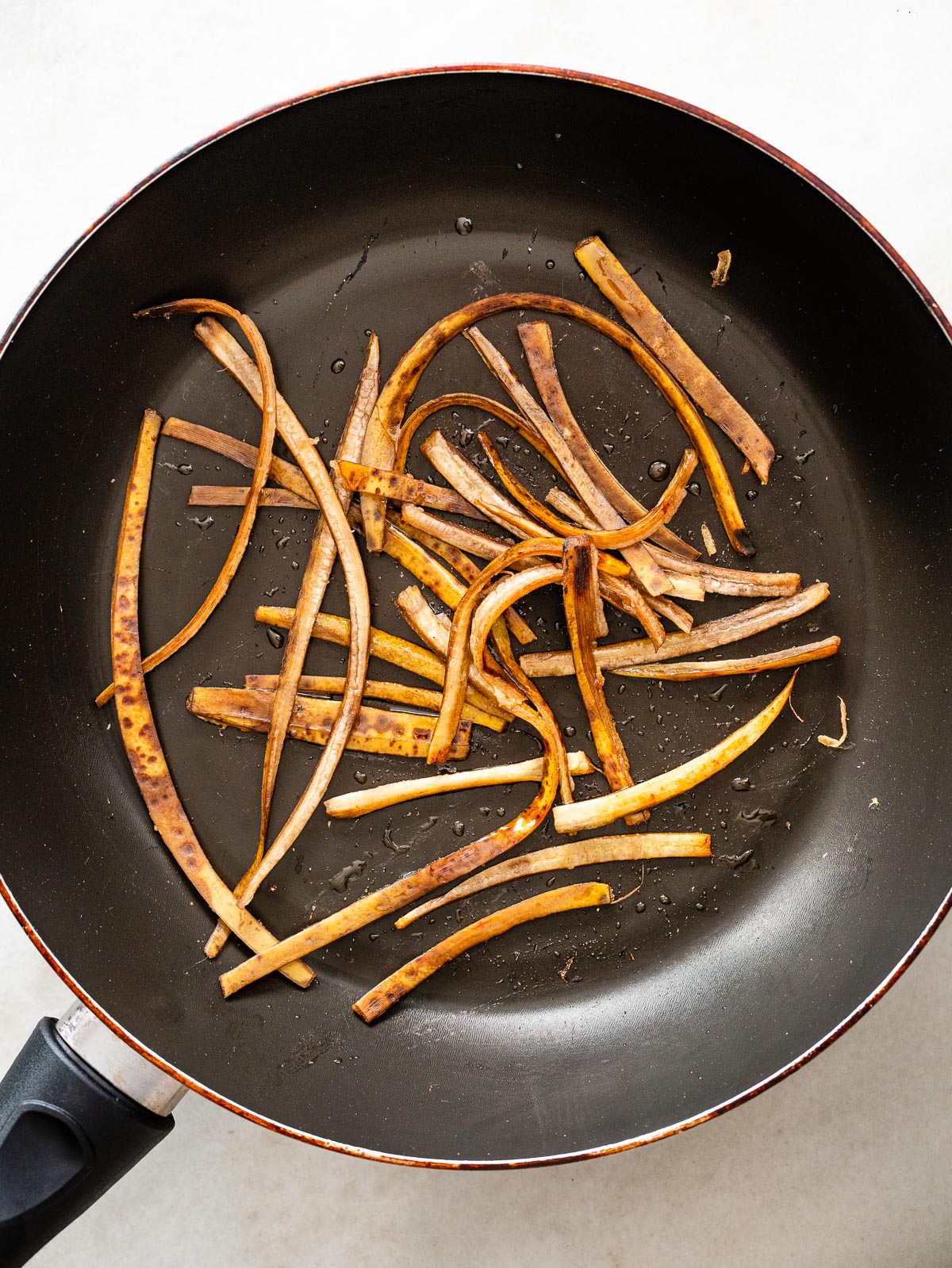 Tiras de cáscara de plátano salteadas en sartén para receta vegana tipo pulled pork