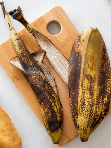 Cáscaras de plátano maduro sobre tabla de madera, listas para su uso en recetas veganas.