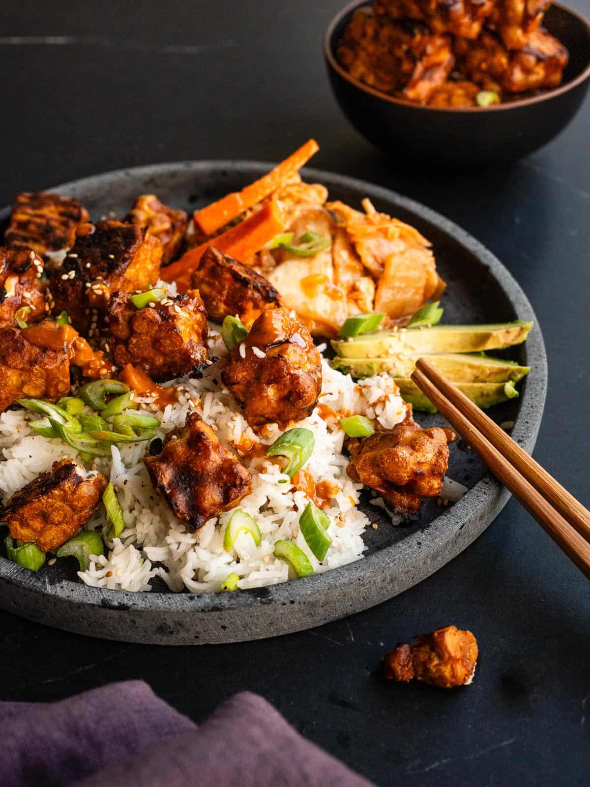 Plato vegano con tempeh al horno, arroz jazmín, kimchi, aguacate y verduras.