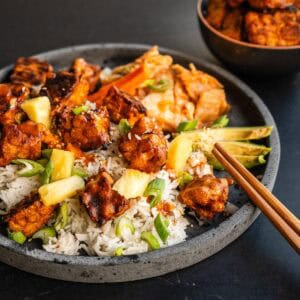 Plato vegano con tempeh al horno crujiente, arroz jazmín, piña, aguacate y kimchi.