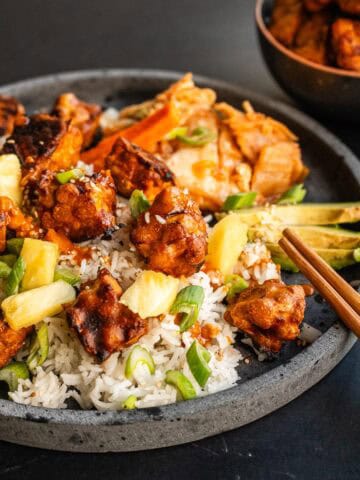Plato vegano con tempeh al horno crujiente, arroz jazmín, piña, aguacate y kimchi.
