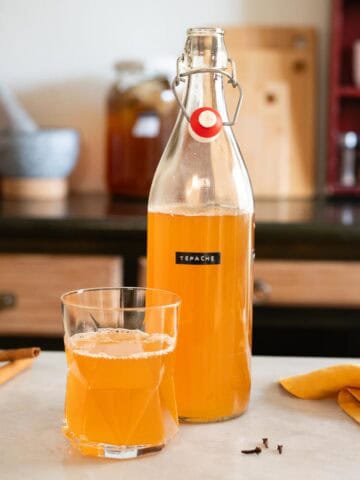 Botella de tepache casero lista para servir como bebida fermentada refrescante.